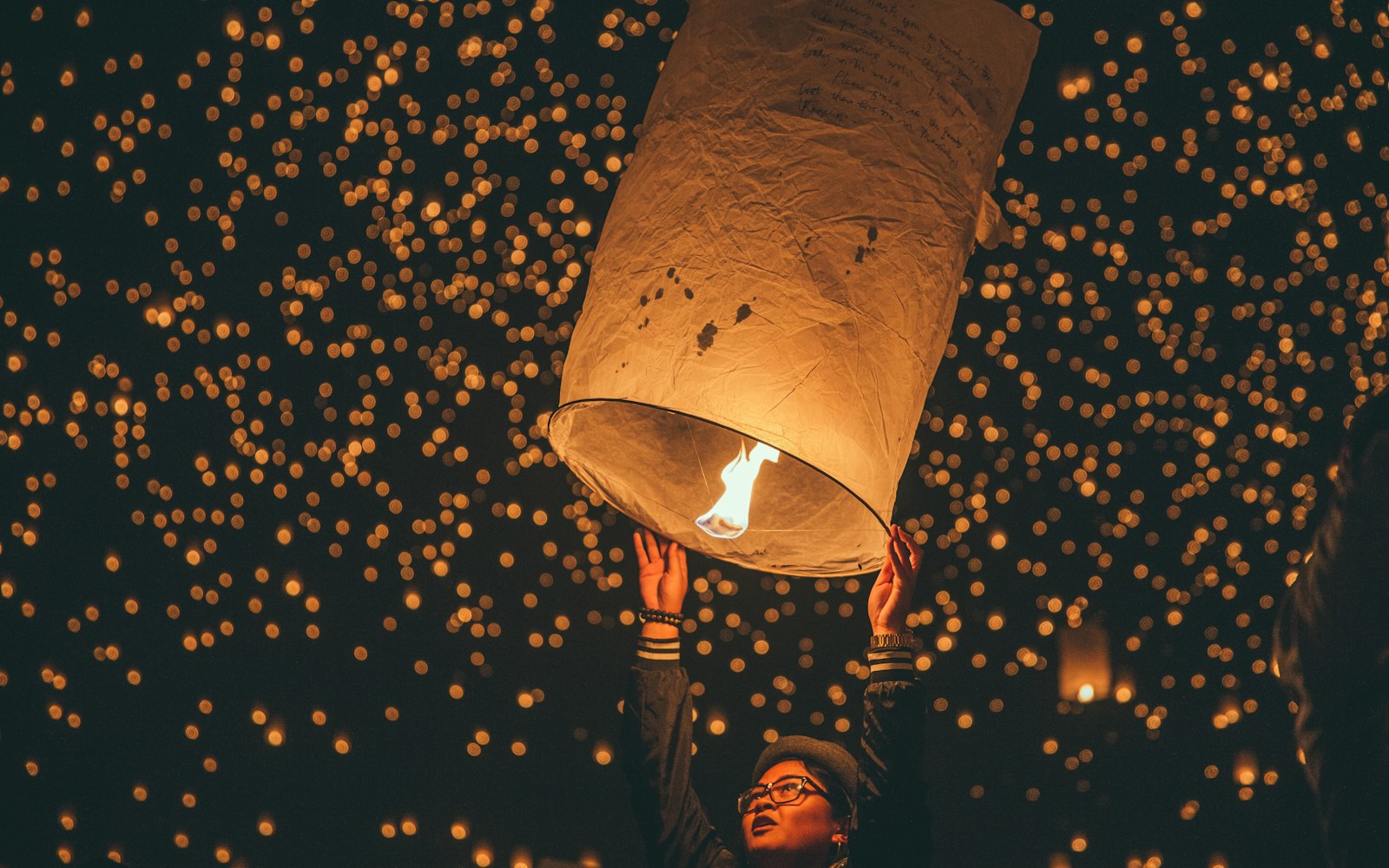 A glowing sky lantern released into a night full of lanterns at a festival in Chiang Mai
