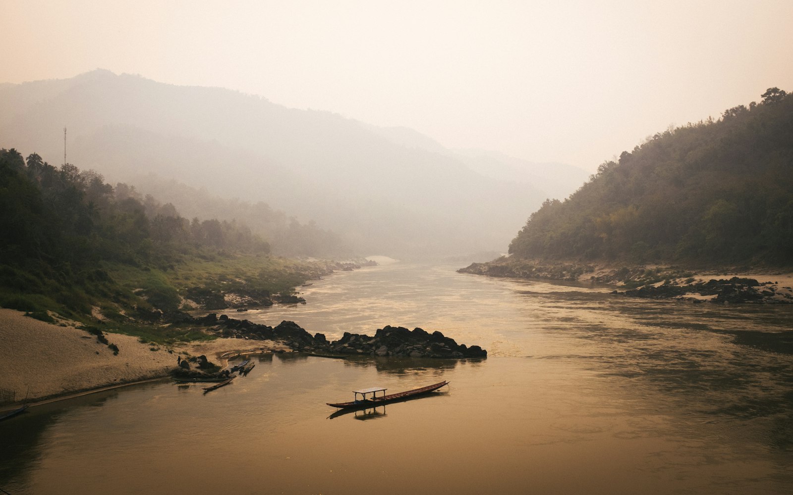 Mist over the Mekong river with a wooden boat near Luang Prabang, Laos