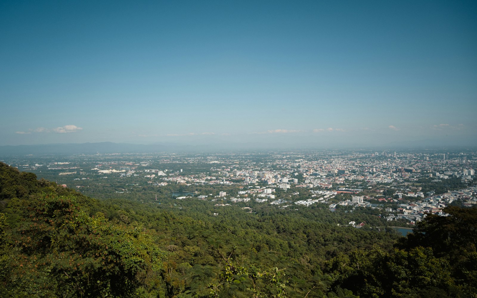 A viewpoint over a Southeast Asian city framed by green hills